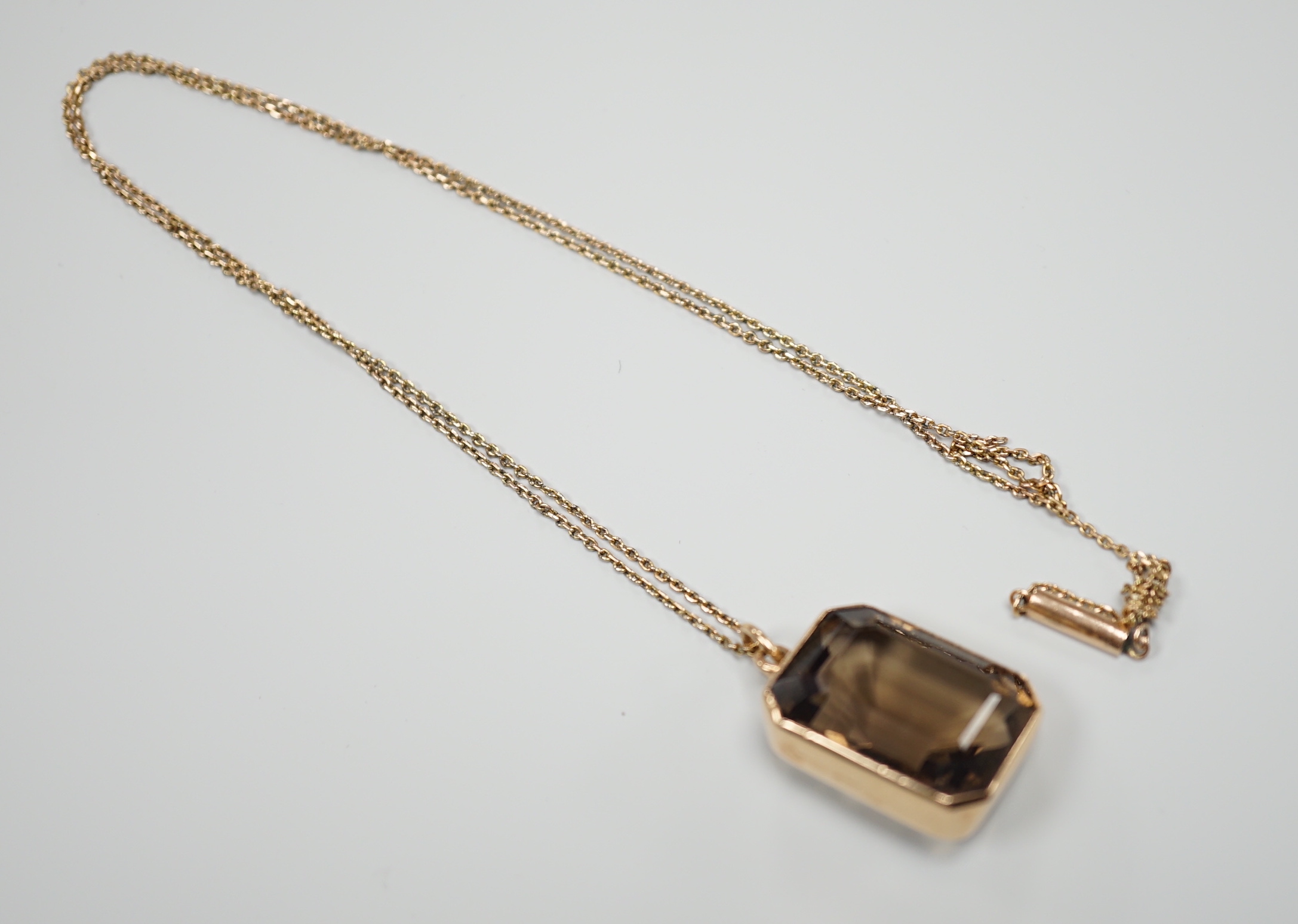 A yellow metal mounted smoky quartz pendant, 24mm, on a yellow metal fine link chain(a.f.), gross weight 15.6 grams.